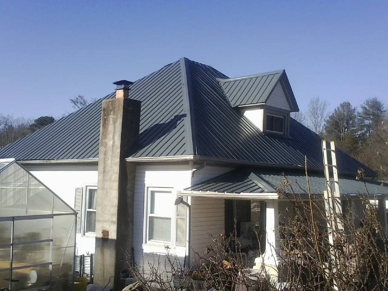 Dark blue standing seam metal roof on a white farmhouse with dormer — Slate & Tile Roof Repair by Roofing Brothers in Mansfield Center