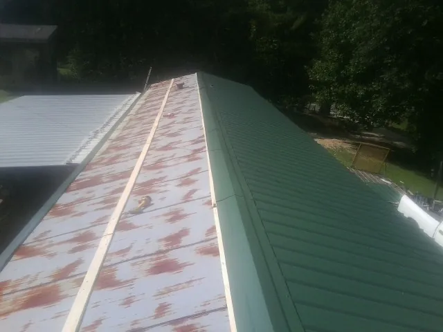 Old rusted panels beside newly installed green metal roofing — Wind Damage Roof Repair by Roofing Brothers in Mansfield Center