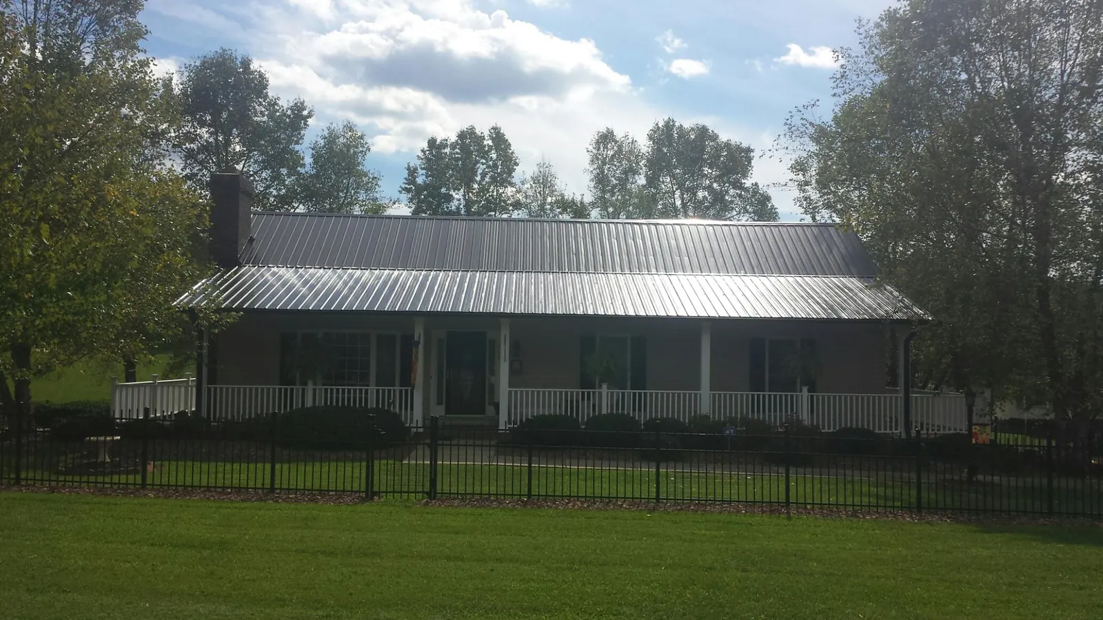 Gray metal roof on a brick ranch with a full width front porch — Gutter Guard Installation work by our crew in Mansfield Center