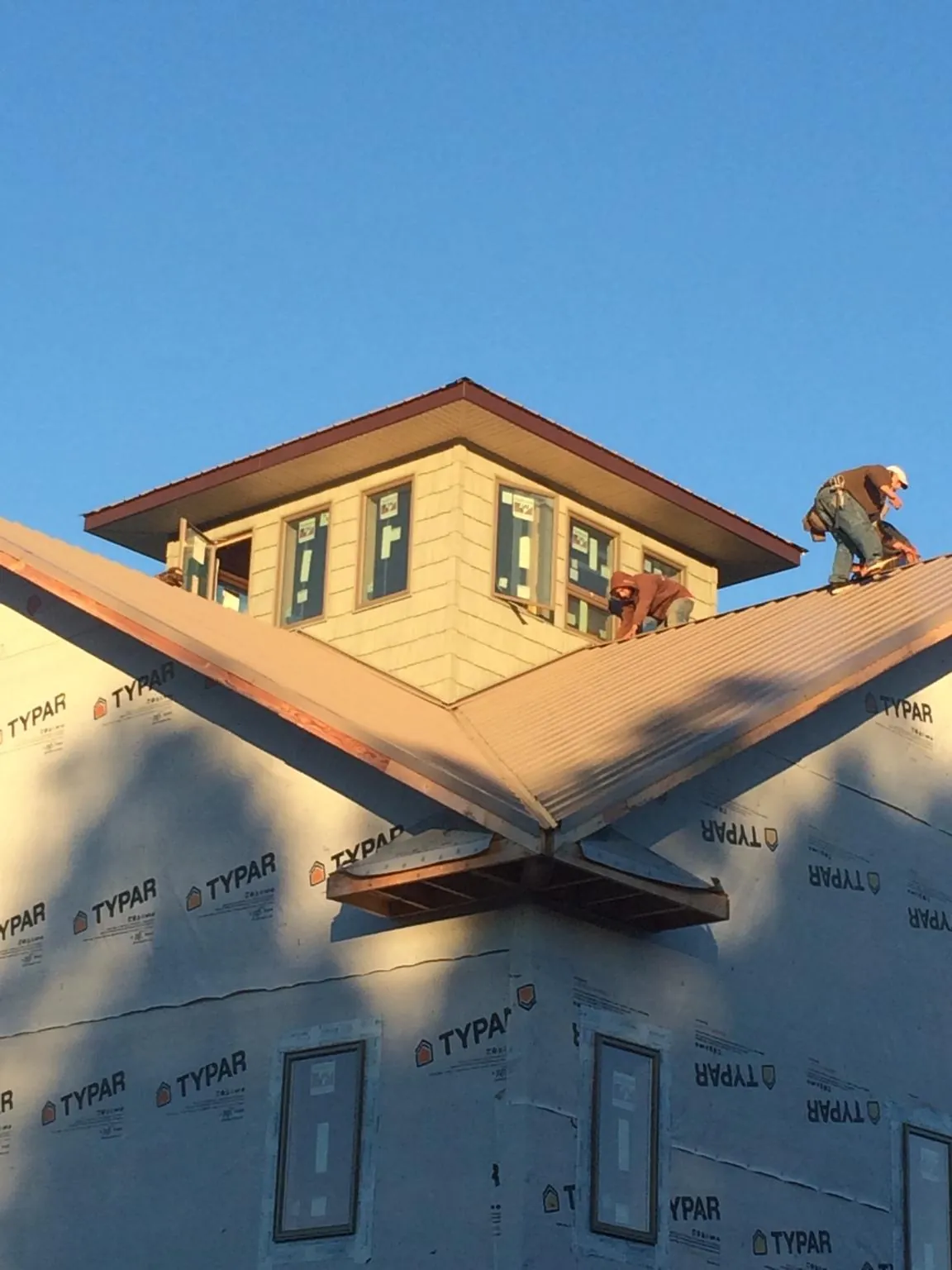 Roofers working around a rooftop cupola on a new metal roof at sunset — Roof Waterproofing in Mansfield Center by Roofing Brothers